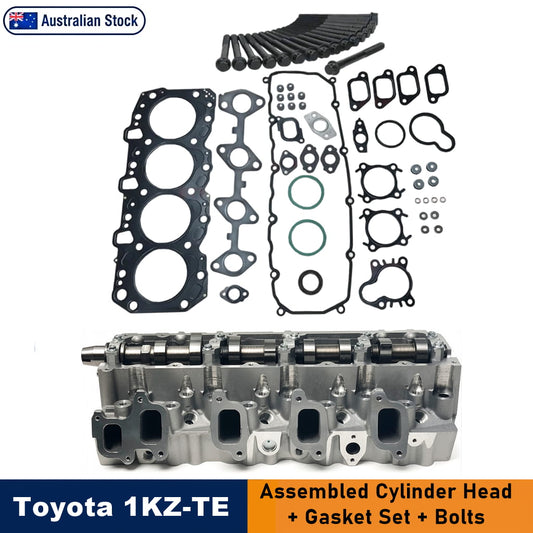 Toyota 1KZ-TE engine cylinder head, showing an assembled silver cylinder head at the bottom and various black and green gaskets, seals, and bolts arranged above it on a white background. Features a 'Toyota 1KZ-TE' label and an 'Australian Stock' badge.